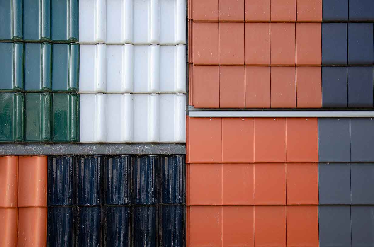 Verschiedene Ziegelfliesen in Grün, Weiß, Schwarz, Orange und Grau, nebeneinander angeordnet.