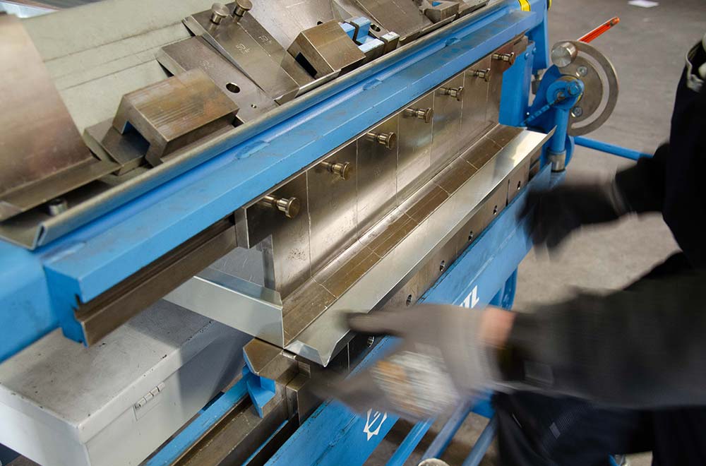 Metallbiegemaschine mit einem Arbeiter, der ein Blech biegt.
