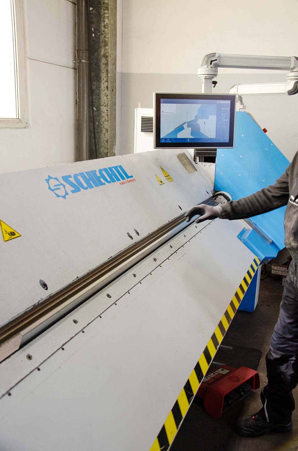 Person bedient eine Schechtl-Biegemaschine mit digitalem Display in einer Werkstatt.